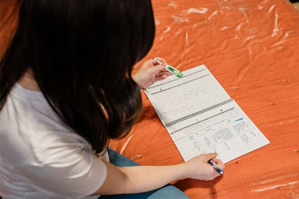 woman tracking fertility stats in notebook